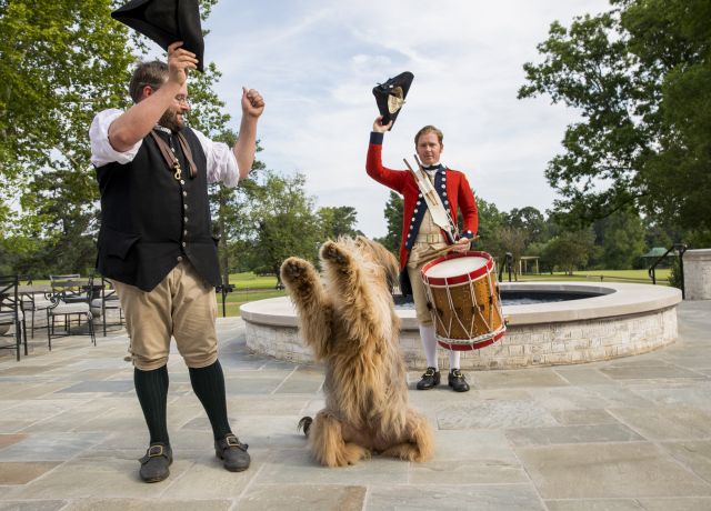 Soldiers in Colonial dress do tricks with dog at Colonial Williamsburg, VA
