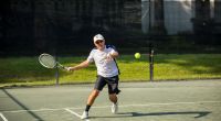 man swings racket at tennis ball
