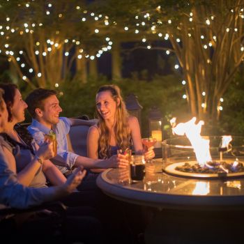 Couples socializing with drinks around fire pit